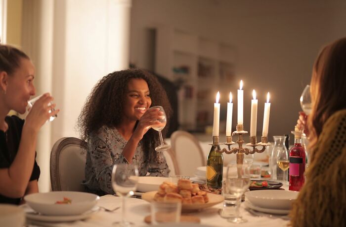Guests smiling and drinking wine at a beautifully lit table, capturing a joyful wild wedding turn.