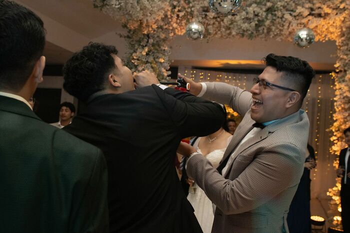 Two men laughing and drinking at a lively wedding reception, a moment from a wild wedding turn.