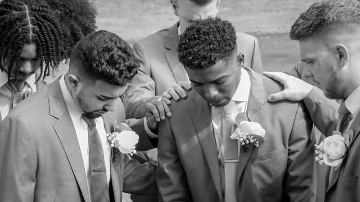 Groomsmen praying together during a wild wedding turn, showing a moment of calm amidst the unexpected.