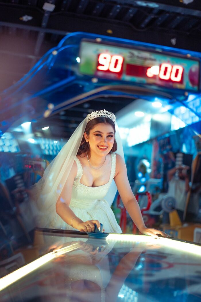 A bride in her wedding dress playing air hockey, a wild turn for the celebration.