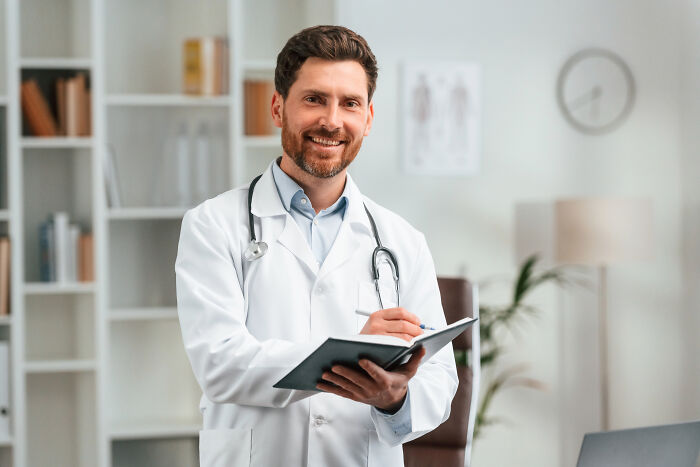 Smiling male doctor with stethoscope holding clipboard
