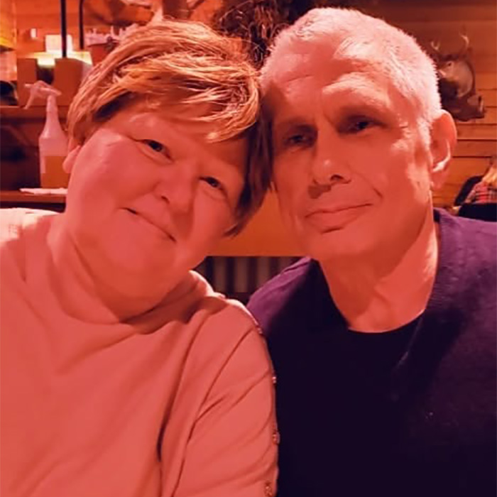 Woman arrested with her husband, smiling together. He passed away after being left on the toilet.