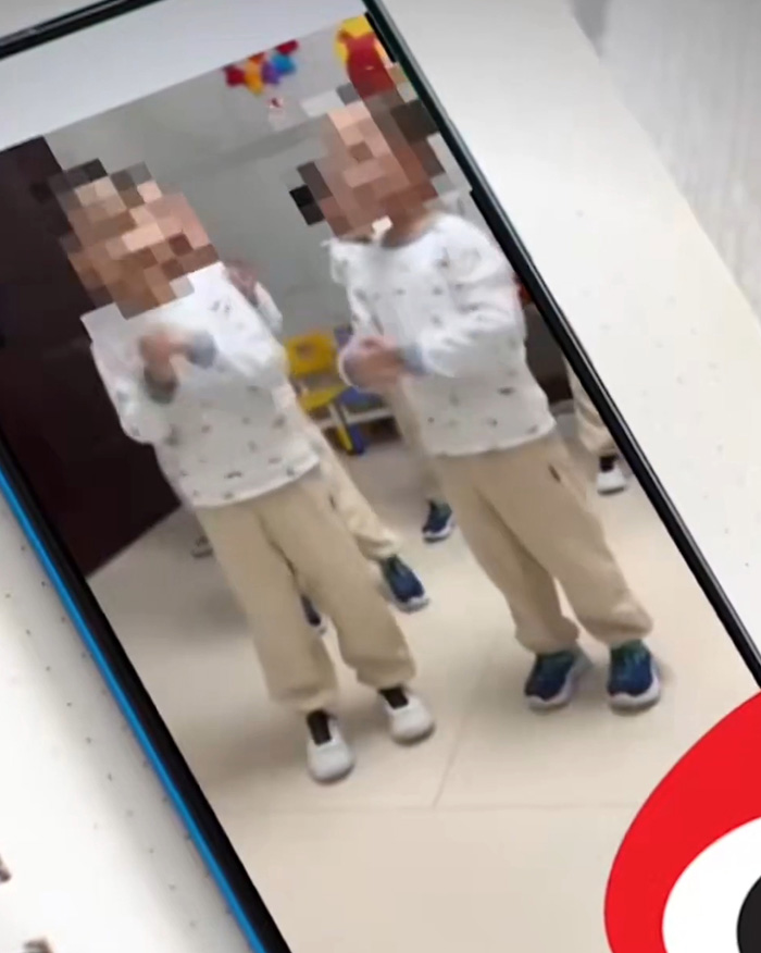 A phone screen displays a video of blurred children, part of a bombshell expos&eacute; about a single dad.