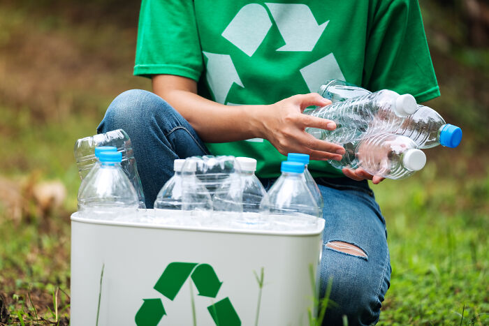A person sorting plastic bottles into a recycling bin, highlighting environmental industry secrets and sustainability efforts.