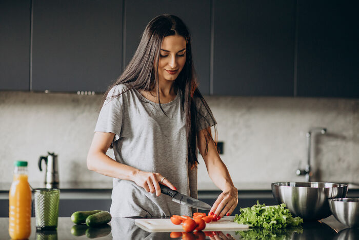 A woman slicing tomatoes in a modern kitchen, reflecting on divorced people