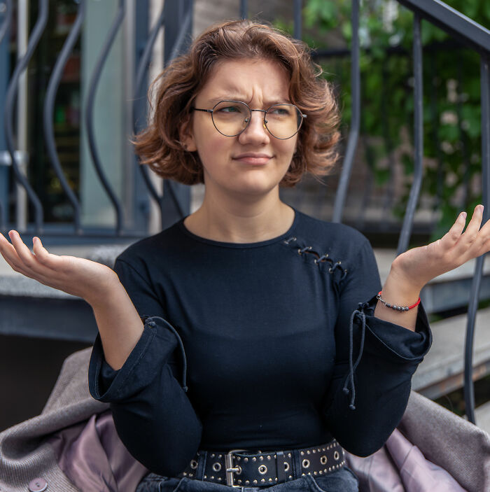A woman shrugging her shoulders, puzzled by dating red flags and questionable dating behavior.