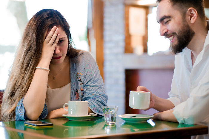 A woman covers her face in embarrassment during a date, illustrating dating red flags and unserious dating moments.