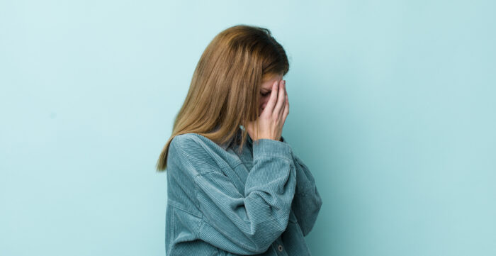 A hurt GF covers her face in distress, symbolizing the pain of a guy who won't marry her or say 'I love you'.