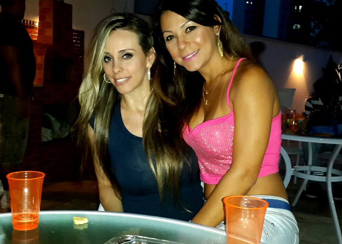 Two women smiling at an outdoor gathering, one of whom underwent 6 cosmetic procedures at once. Two women smiling at an outdoor gathering, one of whom underwent 6 cosmetic procedures at once.