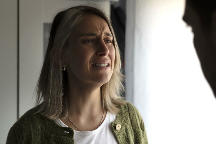 An emotional, crying woman looking at her partner, capturing the pain of divorced people ending a marriage