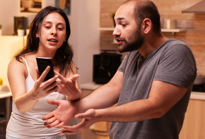A woman showing a phone to an exasperated man, illustrating crazy and unhinged lies.