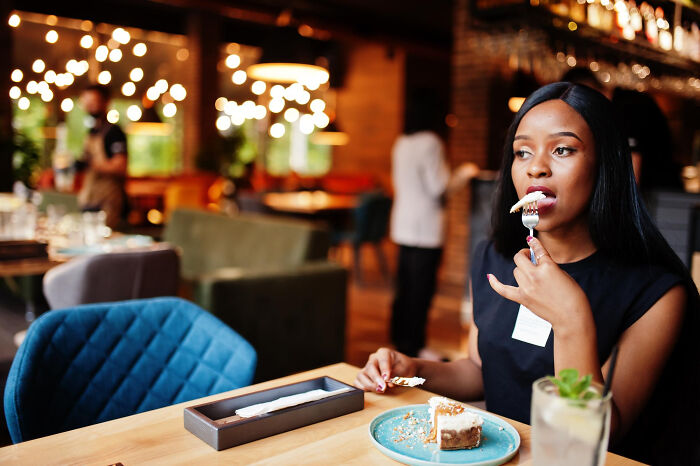 A woman eating cake at a restaurant on her first date A woman eating cake at a restaurant on her first date