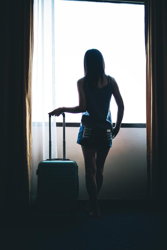 A woman stands with a suitcase, facing a bright window, reflecting on a painful reality check after a relationship nightmare. A woman stands with a suitcase, facing a bright window, reflecting on a painful reality check after a relationship nightmare.