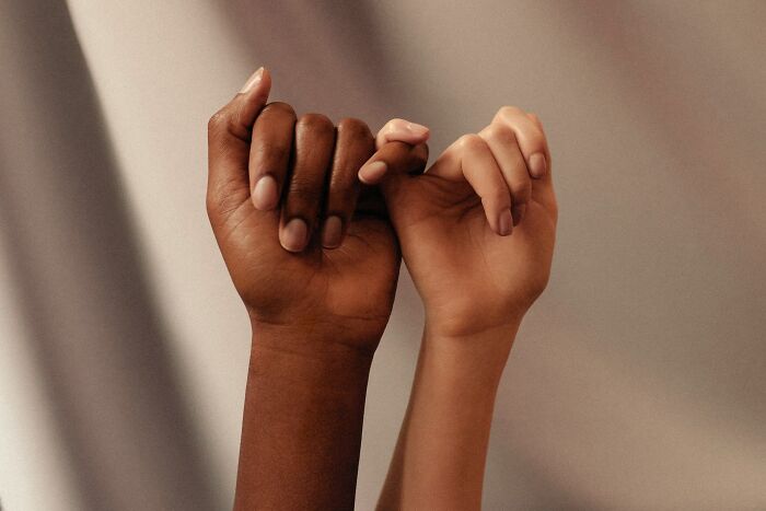 Two people of different races holding hands, showing empathy for strange patients in healthcare.