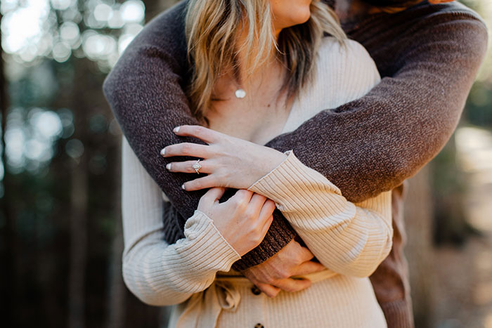 A couple embracing, with a woman wearing an engagement ring, symbolizing a marriage proposal.