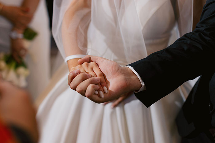 A bride and groom holding hands, representing accepted marriage proposals and the journey of women.