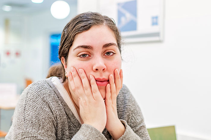 A woman looking troubled with her hands on her face, reflecting emotions related to turning down a marriage proposal.