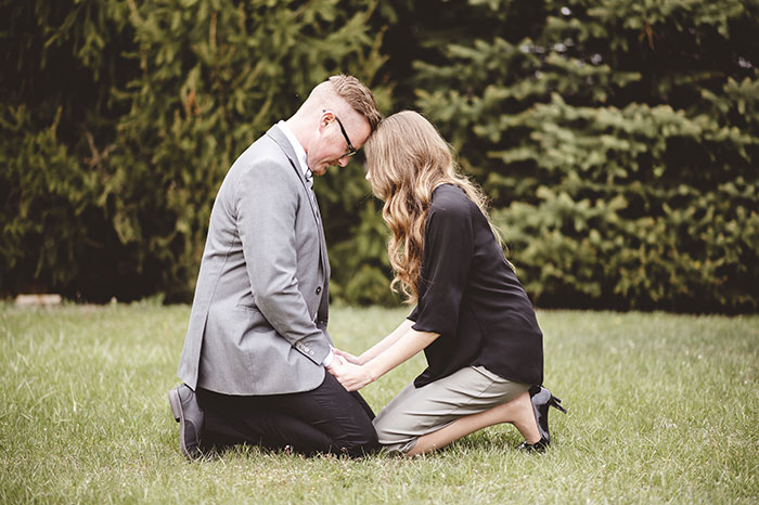 A man and a woman kneeling, holding hands, embodying the commitment after marriage proposals.
