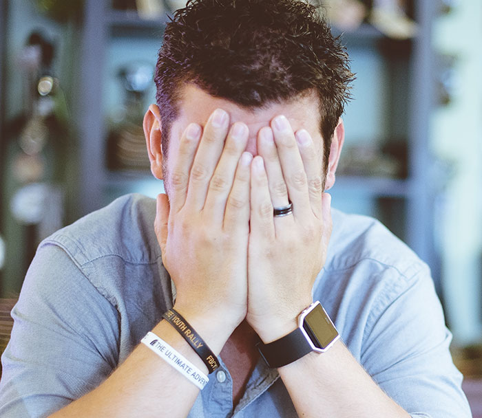 A man covers his face with his hands, feeling sad after a marriage proposal was turned down by a woman.
