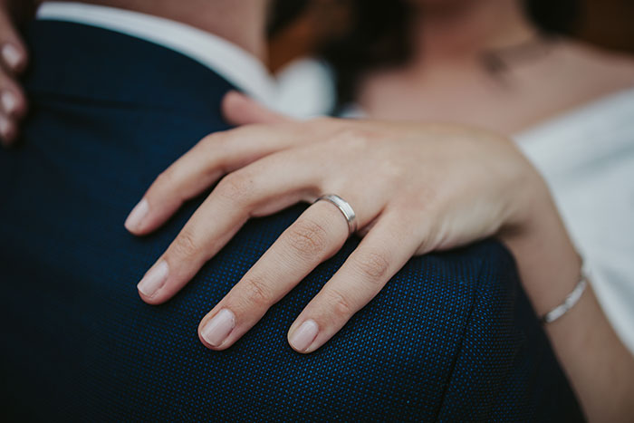 A woman's hand with a ring, resting on a man's shoulder after a marriage proposal.