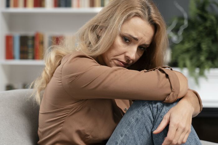 A sad woman sitting on a couch, potentially affected by lies men told her.