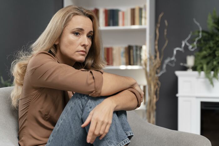 A worried woman sitting on an armchair, thinking about how divorced people face marriage problems