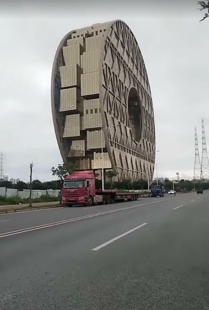Gigantic round coin-shaped building next to a road, evoking a look twice reaction.