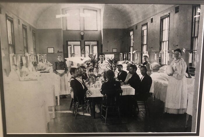 A black and white photo of doctors and nurses in a ward, showing medical history in action.