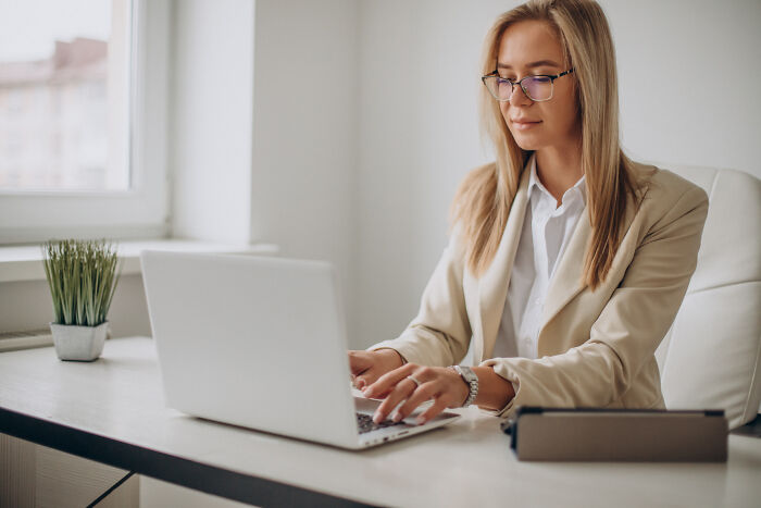 A young female professional working on her laptop, discussing subtle sexism experiences in office