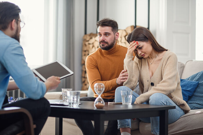 A couple in therapy, with the woman looking upset and the man comforting her, suggesting marital challenges before divorce.