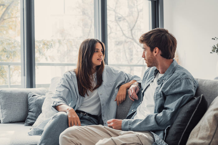 A man and a woman talking on a couch, illustrating instances of subtle sexism.