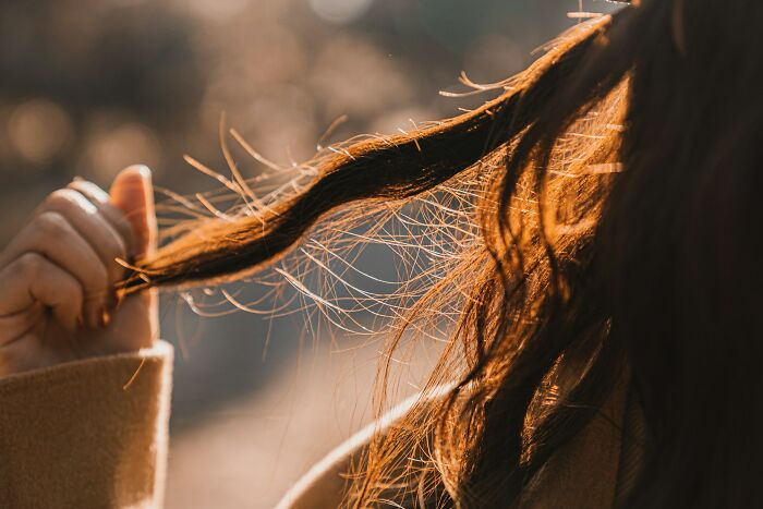 A woman holding a strand of her hair, noticing weirdest body changes in her 30s and 40s