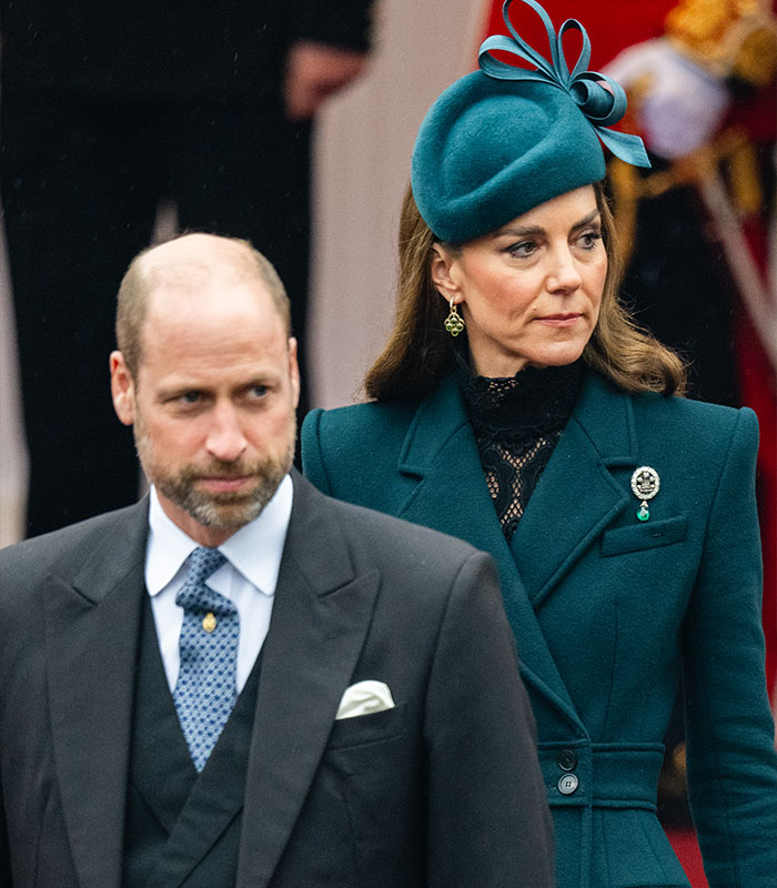 Kate Middleton in a teal coat and hat standing next to Prince William during a royal event