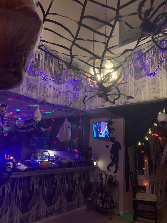 Indoor room covered in giant cobwebs and purple lights as Halloween home decorations.