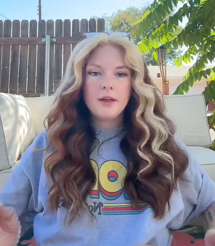 A woman with wavy two-toned hair sitting outside, sharing her story of when she dated a man A woman with wavy two-toned hair sitting outside, sharing her story of when she dated a man