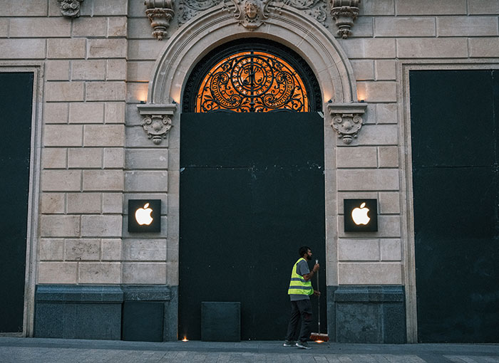 A worker sweeps outside a boarded-up Apple store during a crackdown on looters in France.