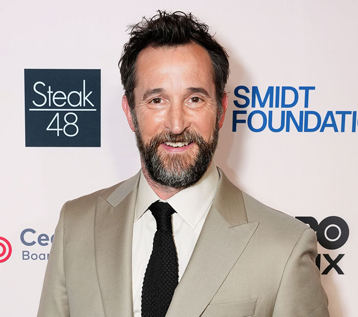 Actor Noah Wyle smiling on the red carpet in a suit and tie