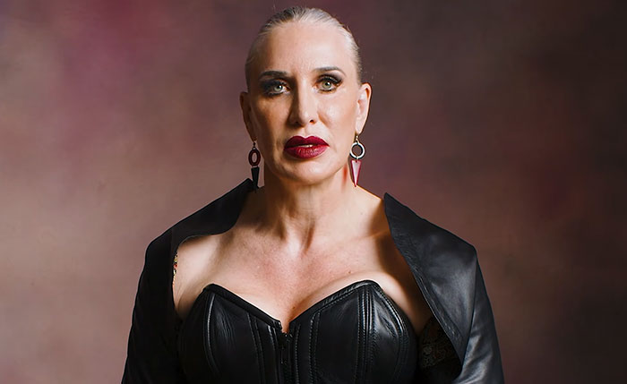 Portrait of a 6 foot 5 inch tall Domme wearing a black leather corset top and red lipstick. Portrait of a 6 foot 5 inch tall Domme wearing a black leather corset top and red lipstick.