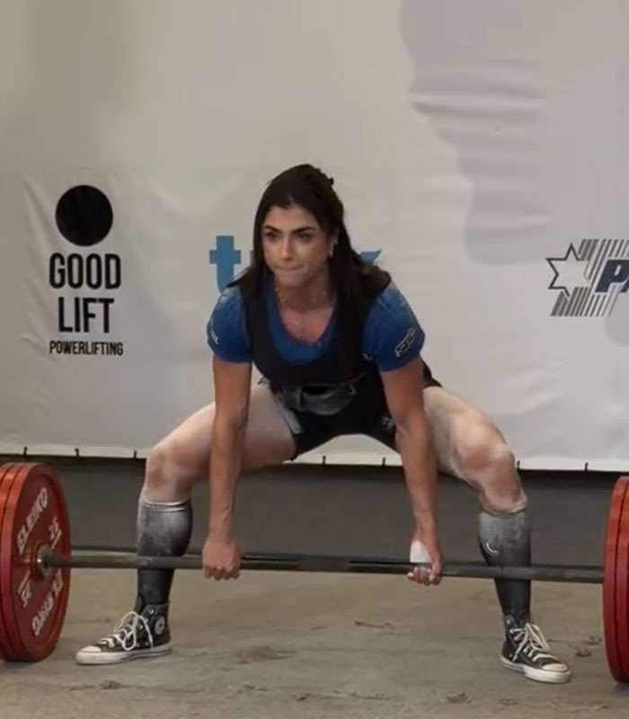 A female professional weightlifter preparing to lift a heavy barbell during a powerlifting competition. A female professional weightlifter preparing to lift a heavy barbell during a powerlifting competition.