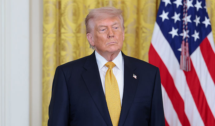 Donald Trump standing in front of an American flag during an event related to the Trump Mobile phone
