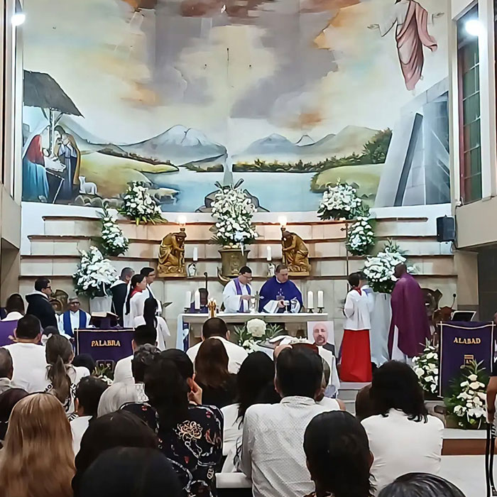 Congregation attending church mass with priests at altar and floral arrangements Congregation attending church mass with priests at altar and floral arrangements