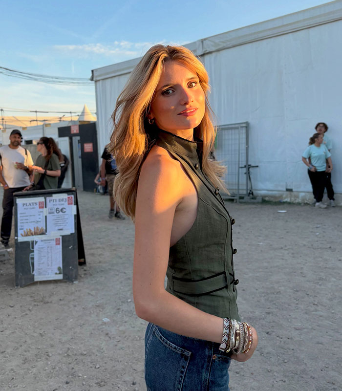 An influencer posing outdoors in an olive green halter top and jeans during sunset