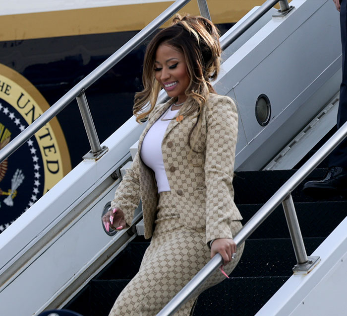 Nicki Minaj descending airplane stairs wearing a patterned Gucci suit