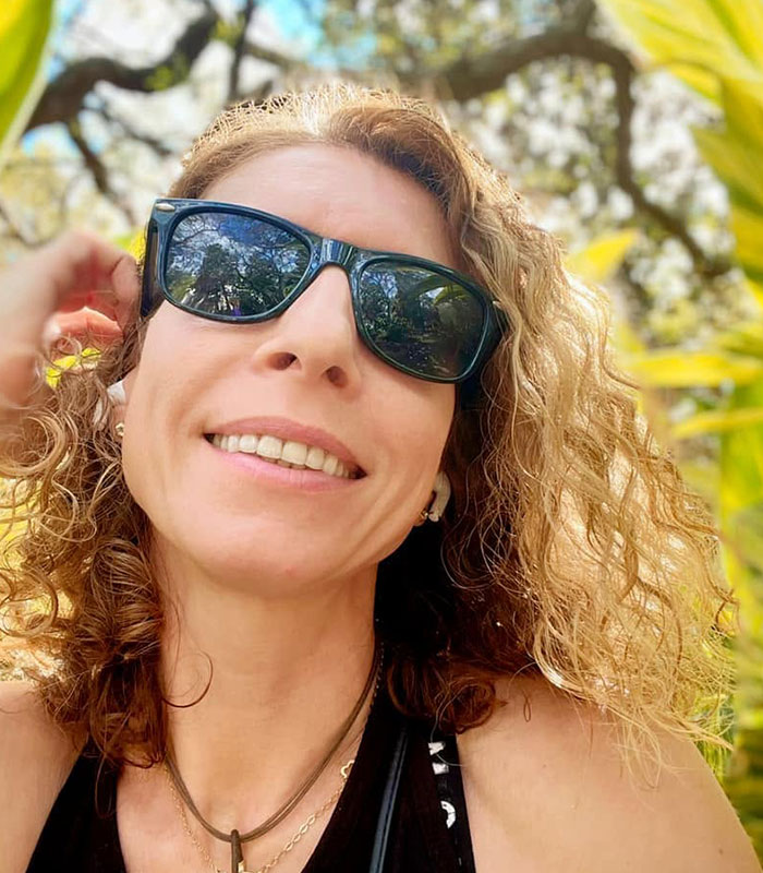 Close-up photo of the mom smiling in sunglasses during a trip, related to a story of leaving kids home alone.
