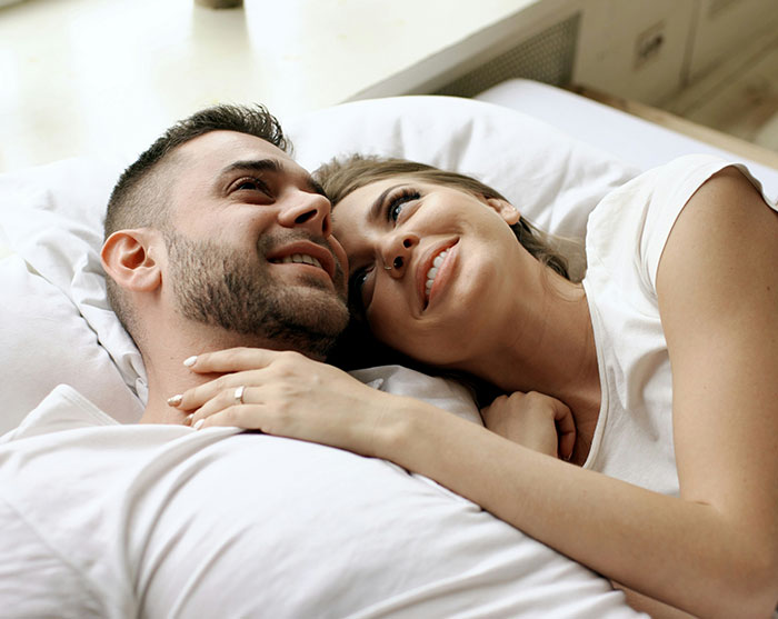 A happy couple lying together in bed engaging in an intimate bedroom activity. A happy couple lying together in bed engaging in an intimate bedroom activity.