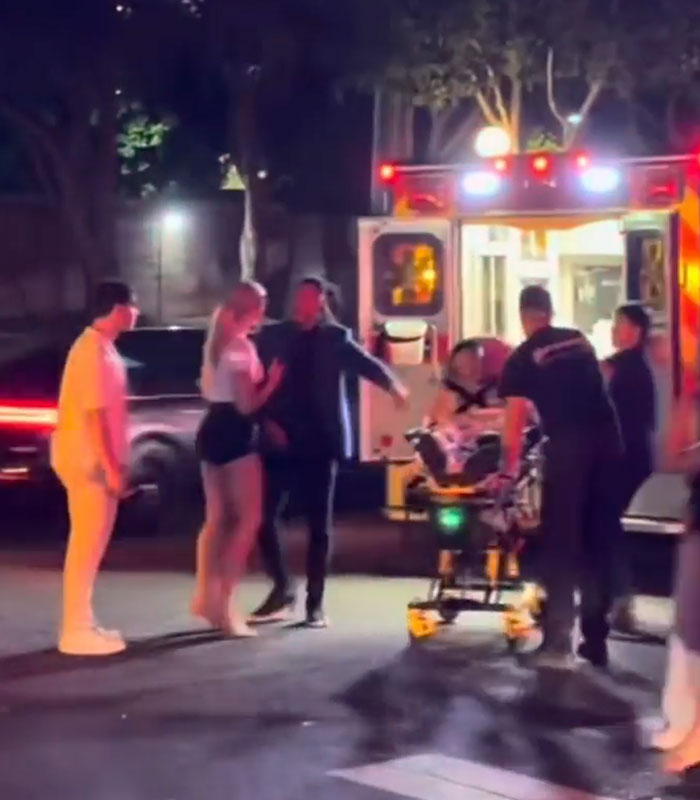 A group of people and paramedic staff near an ambulance on a city street A group of people and paramedic staff near an ambulance on a city street