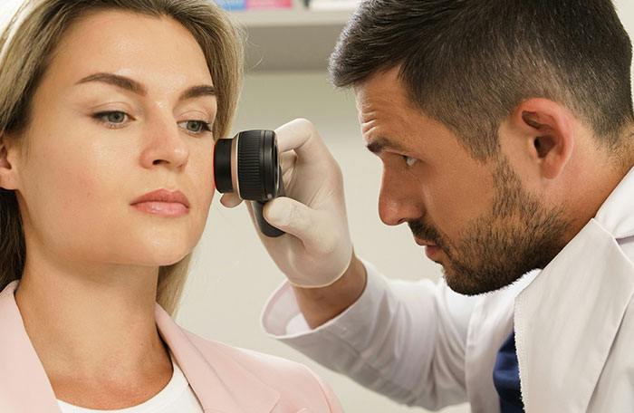 Doctor inspecting patient's skin for white spot clusters