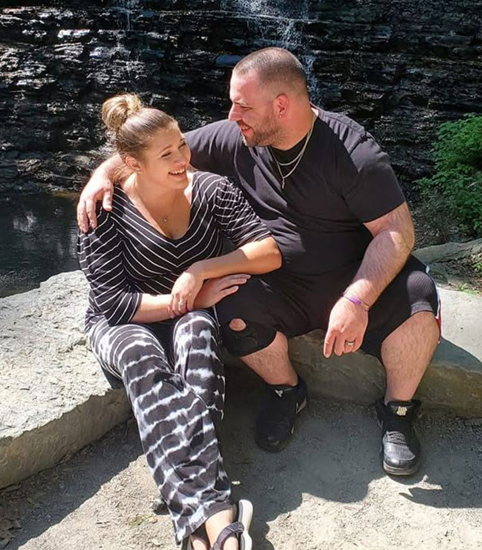Couple smiling and sitting outdoors near waterfall