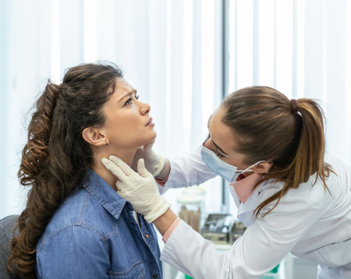 A doctor examining a patient neck during a medical checkup for rising cancer rates. A doctor examining a patient neck during a medical checkup for rising cancer rates.