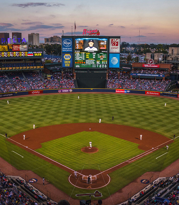 Wide view of a packed baseball stadium during a game at sunset, illustrating a Dodgers fan story.